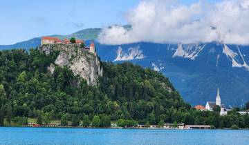A scenic lake with mountains and cloudy sky in the background.