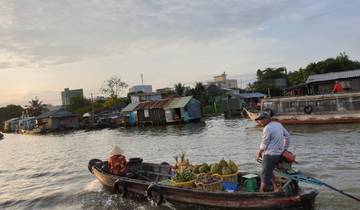 Man in a boat on a river with houses along the shore.
