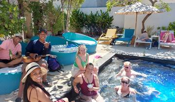 People relaxing in and around a pool with drinks and musical instruments.