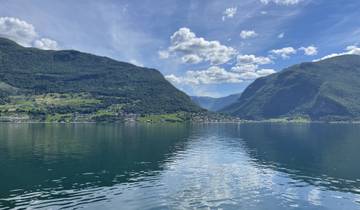 A scenic view of a fjord with mountains and a reflection on water.