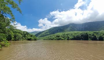 Brown river with green hills in the background.