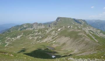 Mountain ridge with green slopes and snow patches.