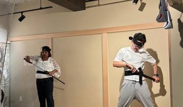 Two people practicing martial arts with swords indoors.
