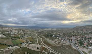 Panoramic view of a landscape with fields, mountains, and a small town.