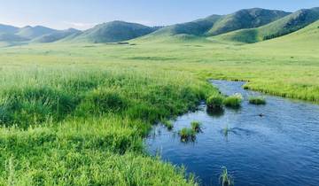 Serene landscape of a stream running through green fields.