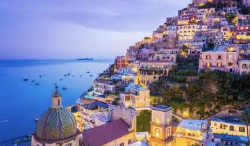 Scenic view of Positano at twilight with illuminated buildings.