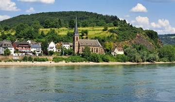 Riverside village with a church and houses on a sunny day.