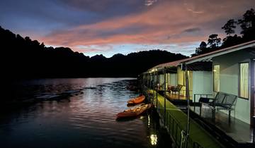 Floating accommodation with kayaks on a calm lake at dusk.