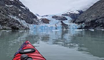 Kayak on a calm water body with a glacier in the background.