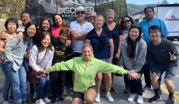 Large tour group posing happily outdoors with mountains in background.
