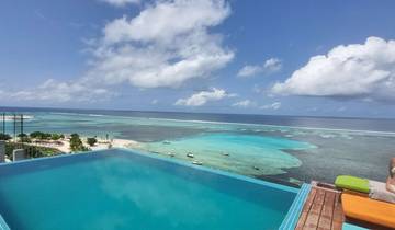 Infinity pool overlooking a beach with tropical waters.