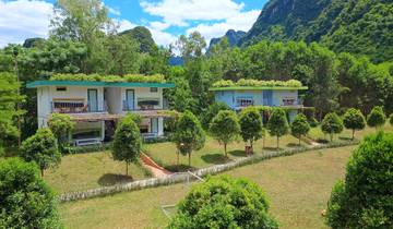 Two modern villas surrounded by a lush green garden.