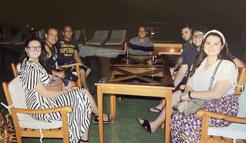 Group of people sitting around a table outdoors at night.