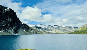 Panoramic view of a tranquil lake surrounded by snow-capped mountains.
