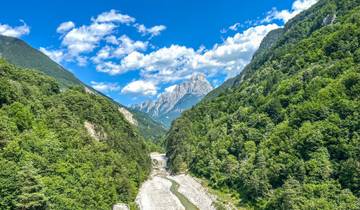 A scenic view of a river canyon flanked by forested mountains.