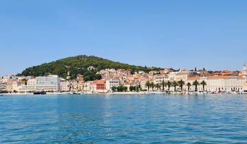 A panoramic view of a coastal city with a hill in the background.