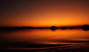 Stunning view of a sunset over a calm river with a striking orange sky.