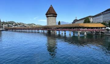 Historic wooden bridge with flowers crossing a body of water.