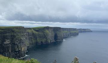 Dramatic cliffs facing the ocean under a cloudy sky.