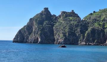 A rocky cliff with blue sky and ocean view.