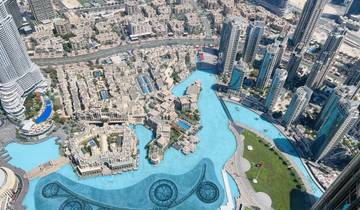 Aerial view of a cityscape with modern skyscrapers and a large water feature.