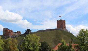 Tower with flag on a hilltop against a blue sky.