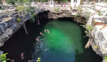 People swimming in a cenote with clear green water.