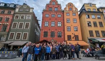 A group of people in front of colorful historic buildings in a European square.