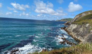 Rocky coastline with crashing waves under a bright blue sky.