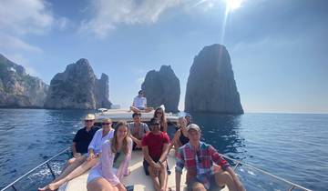 Group of people on a boat with cliffs in the background.