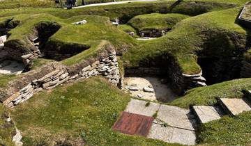 Ruins of ancient stone structures on a grassy site.