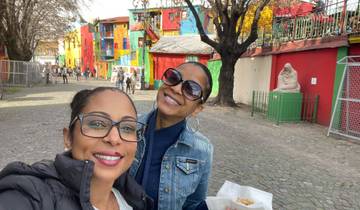 Two women posing with colorful buildings in the background