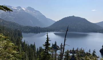 Serene mountain lake surrounded by forest and peaks.