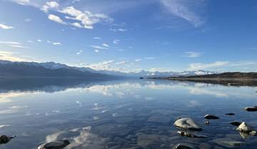 Calm lake with reflections of mountains and clear sky.