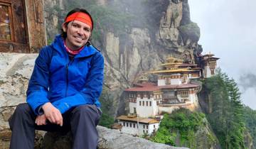 Person posing in front of a traditional Bhutanese monastery.