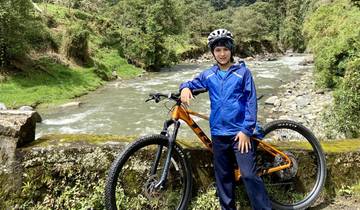 Person with a helmet and bicycle beside a scenic river.