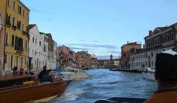 Venetian canal bustling with boats under a blue sky.