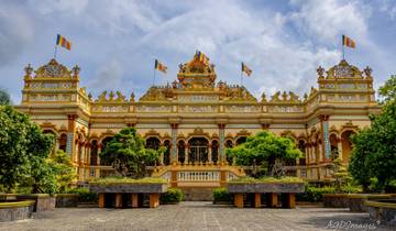 Ornate Buddhist temple with flags and trees.