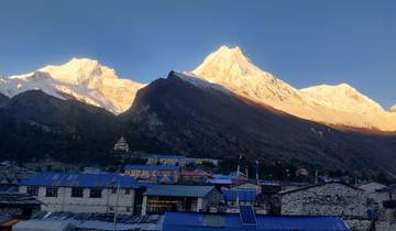 Sunrise over a mountain village with snowy peaks.