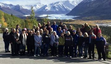 A large group posing with a glacier and mountains in the background.