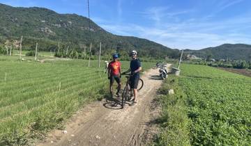 Two people on bicycles in a green rural landscape.