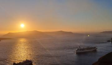 Sunset over the sea with a cruise ship in the water.