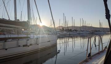 Sailboats docked at a marina with mountains in the background.