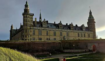 Historic castle viewed in a dramatic light with people walking below.