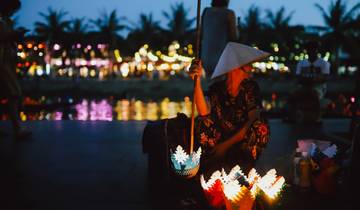 Silhouette of a woman with lanterns by a river at night
