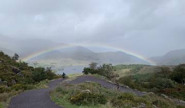 A scenic view of a rainbow over a hilly landscape.