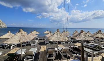 Beach with straw umbrellas and loungers under a bright sky.