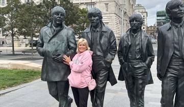 Statues of four men and a person posing with them. Large building in the background.