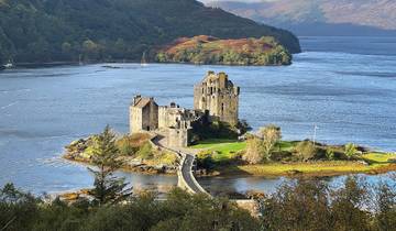 Castle situated on an island connected by a bridge, surrounded by a lake.