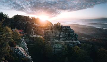 Dramatic sunrise over a rocky landscape with a house nestled on the cliffs.